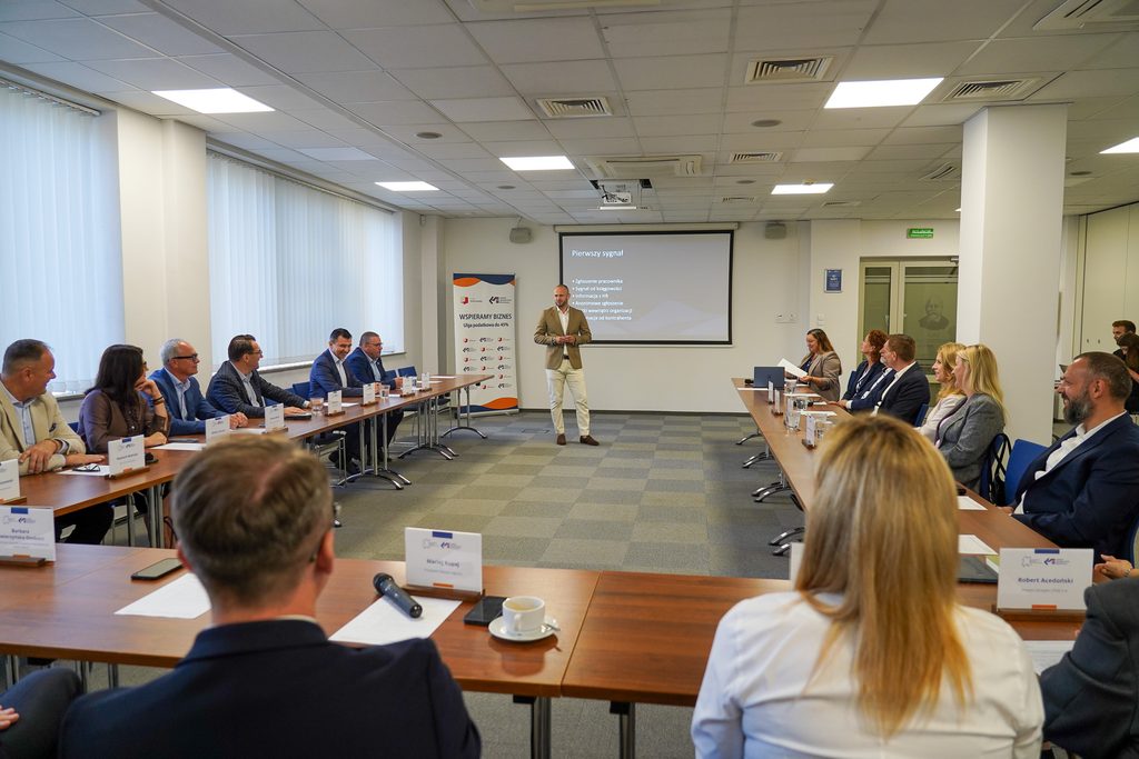 mężczyzna przemawia, ludzie siedzą za stołami